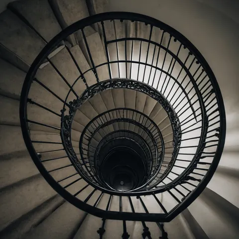 Spiral staircase with black iron railings and concrete steps viewed from above
